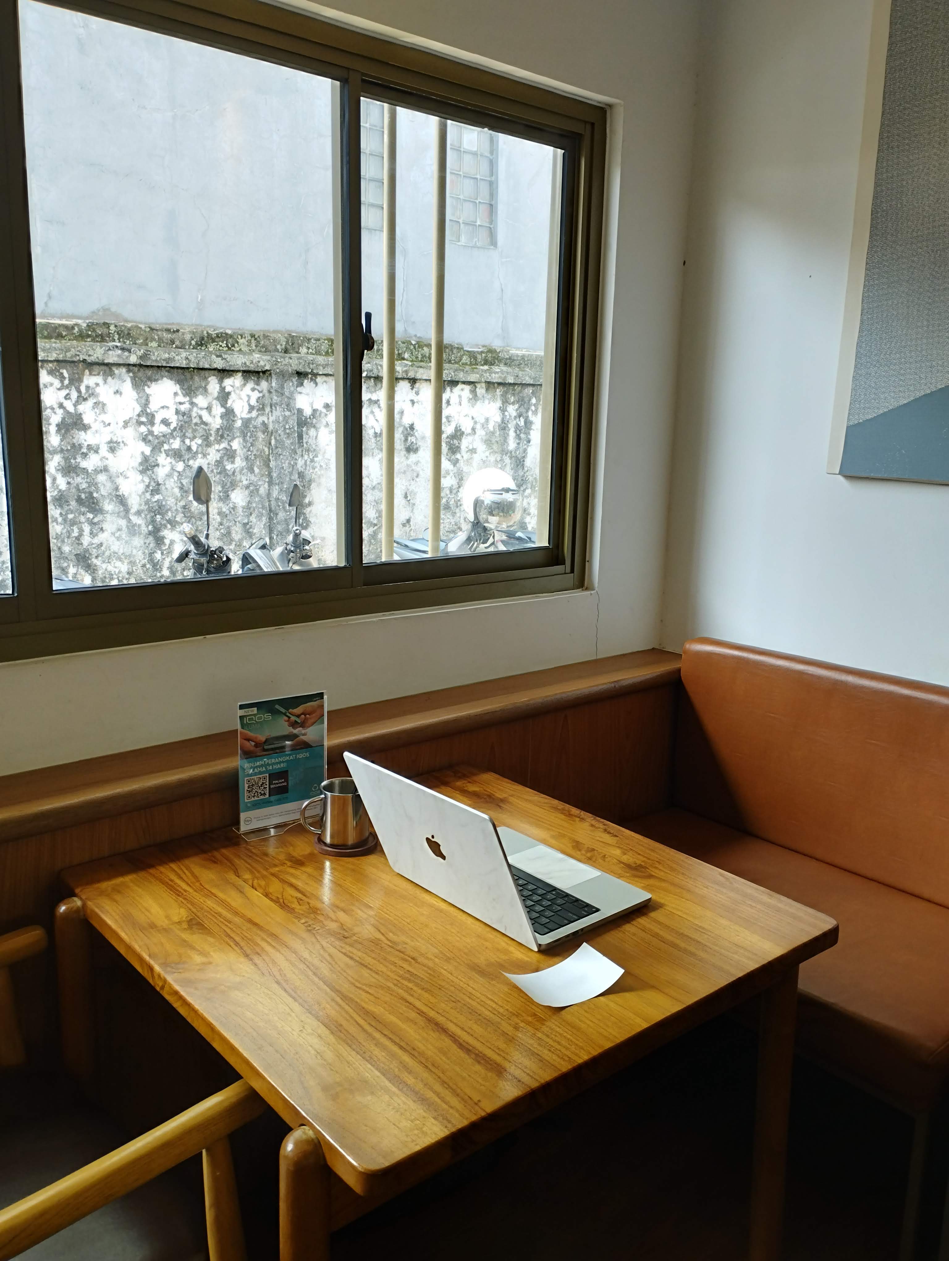 A macbook on a wooden table with no external monitor or mouse.